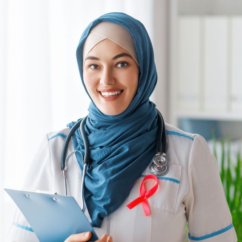 A smiling female healthcare professional wearing a blue headscarf and stethoscope, holding a clipboard.