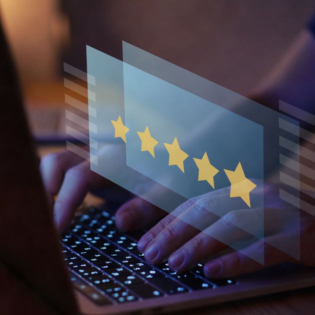 Person typing on a laptop with a digital overlay of five yellow stars, representing online reviews or ratings.
